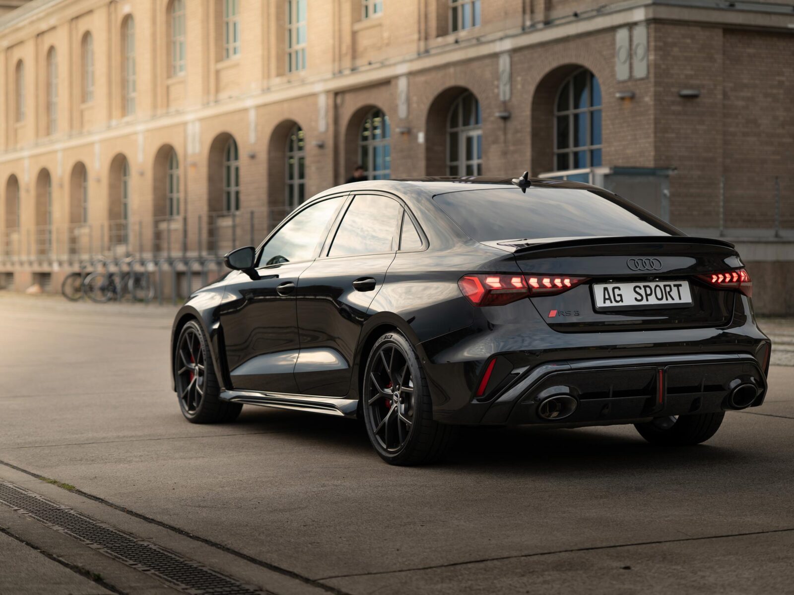 seitenansicht des Audi RS3 in schwarz. Im Hintergrund ist ein Hafenspeicher am Spreeufer von Berlin zu sehn.