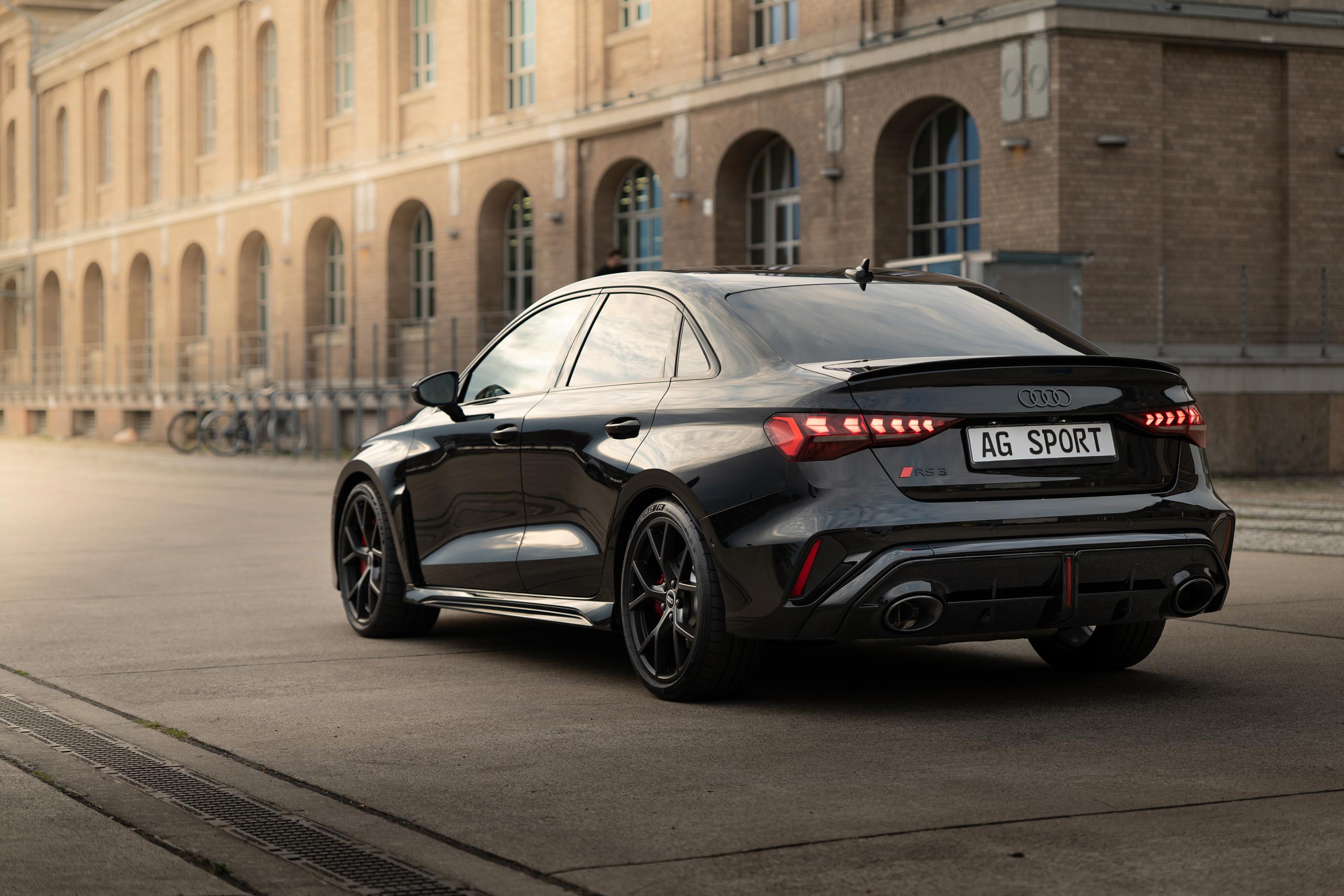 seitenansicht des Audi RS3 in schwarz. Im Hintergrund ist ein Hafenspeicher am Spreeufer von Berlin zu sehn.