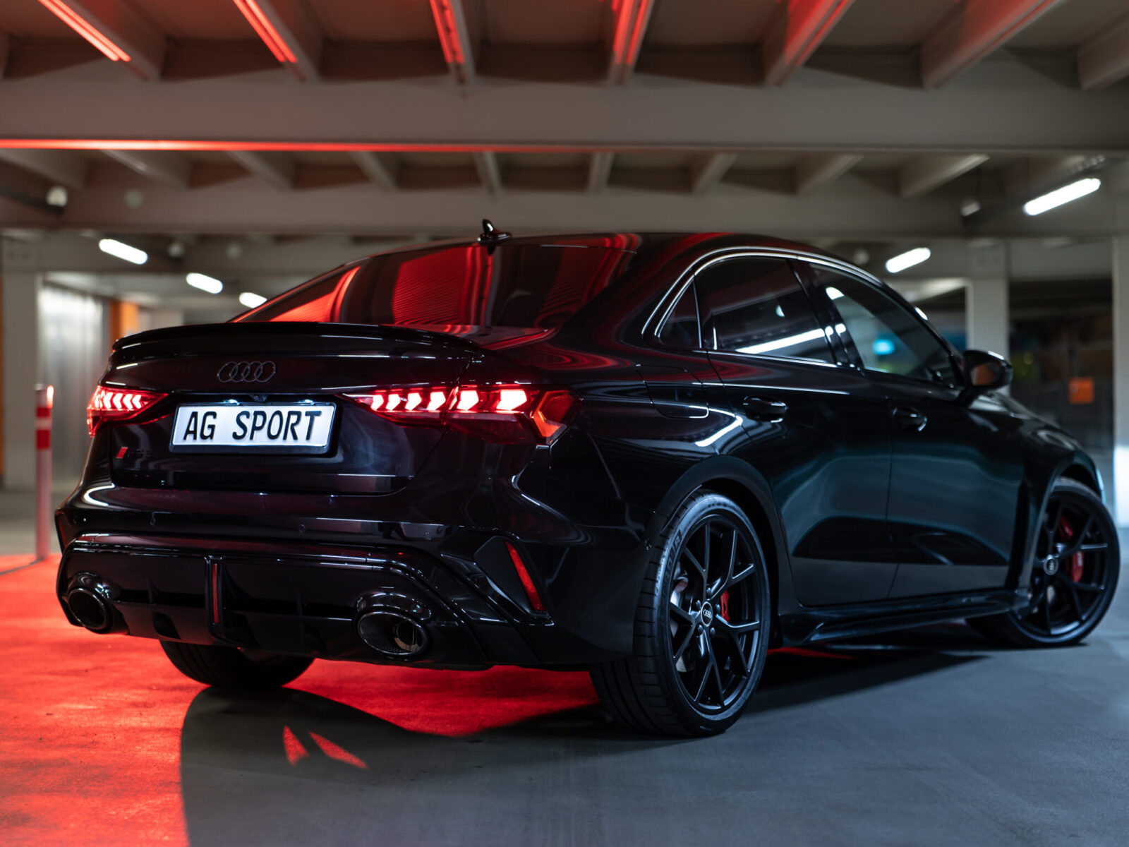 Der Audi RS3 steht in einem Berliner Parkhaus und es ist das Heck mit dem Kennzeichen "AG-Sport" zu sehen.